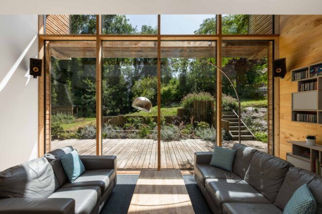 A living room with floor-to-ceiling windows facing a forest landscape