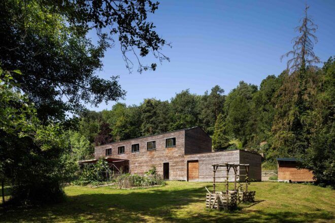 A far off shot of the wood house against the valley landscape