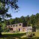 A far off shot of the wood house against the valley landscape
