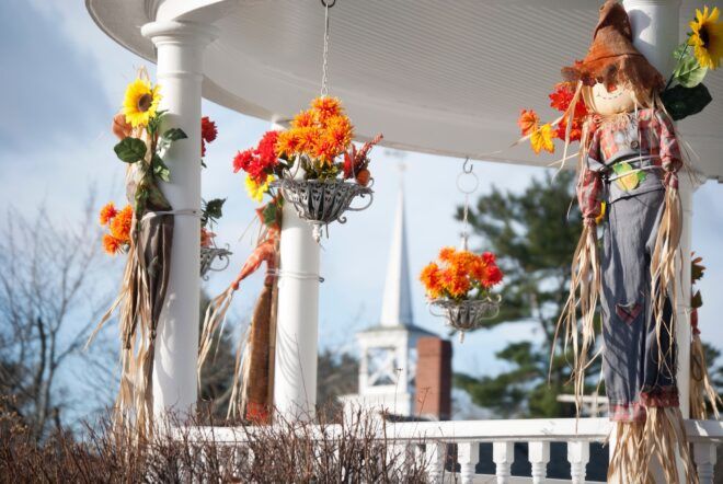 A scarecrow hangs on a white house frame