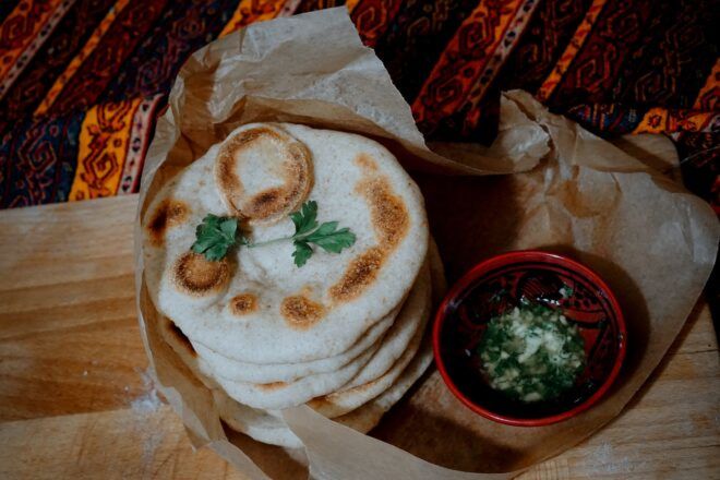 A pile of naan next to a dish of sauce.