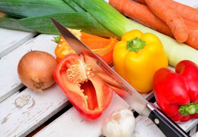 A knife chopping into a pile of vegetables.