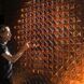 A person pointing a finger at a gold wall that is designed with multiple holes
