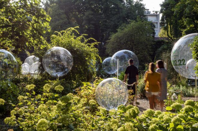 Bubbles floating in a garden area with people walking through and viewing the exhibit