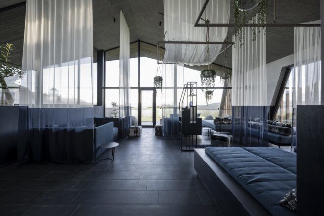 A seating area with white curtains draped from the ceiling and blue decor