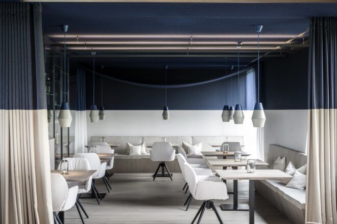 A dining area with white chairs and the walls half painted a dark blue color
