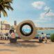 A large circle ring that it has a see through middle sits by the ocean