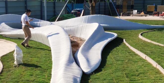 An abstract, 3D-printed sculpture on a green lawn.