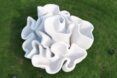 An abstract, 3D-printed sculpture on a green lawn.