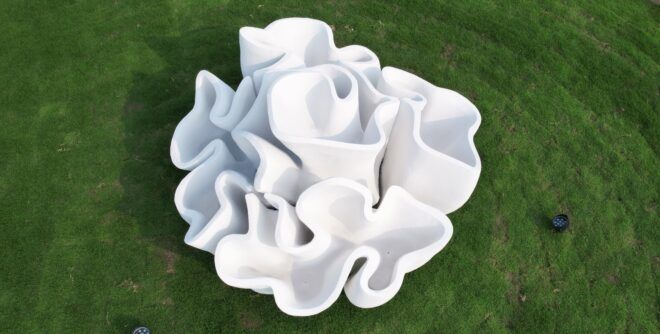 An abstract, 3D-printed sculpture on a green lawn.
