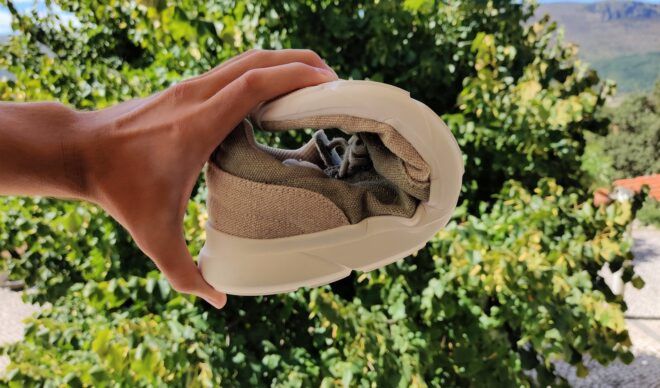 A hand bending a shoe from the tip of it bent back to the feet insert part of it