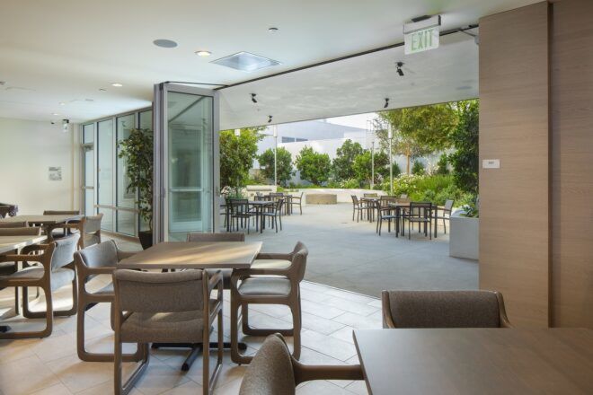 A room with chairs and tables opening up to the outside dining area