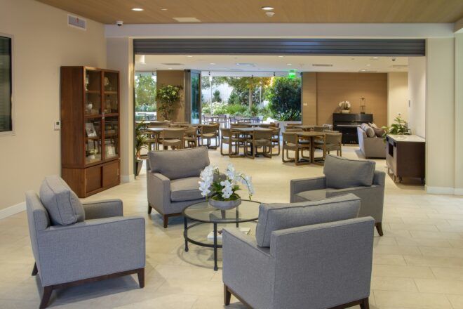 Inside living room with four grey sofas surrounding a glass table