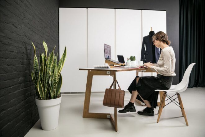 A person sitting at a desk with a plant next to them