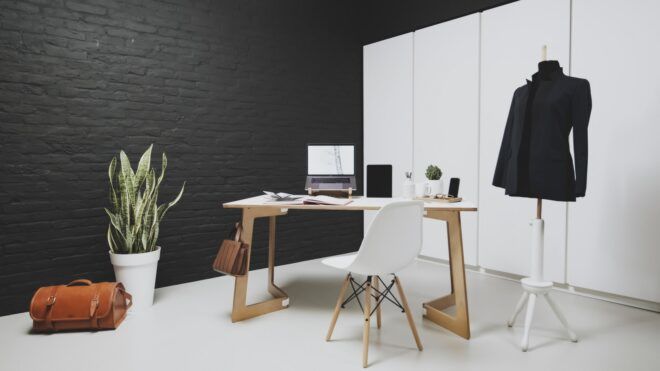 A desk with a laptop and a white chair with a coat rack next to it