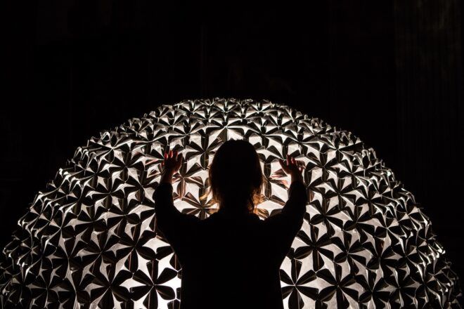 A person touching a dome structure that has multiple cutouts