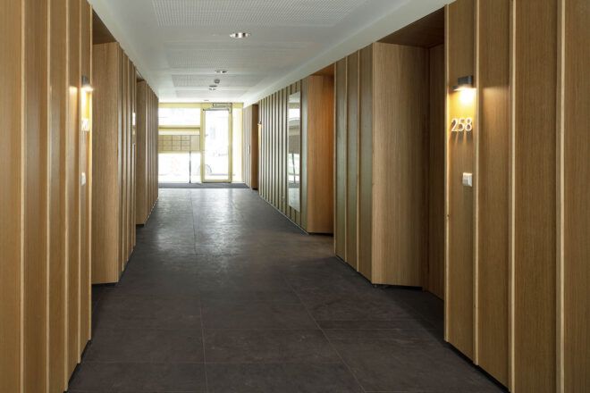 A hallway with wood walls and dark flooring.