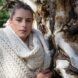 A woman leaning against a tree wearing a woolen scarf