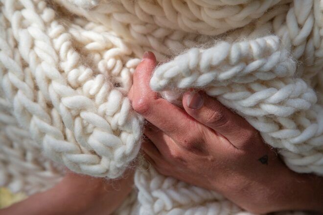 Hands touching a white wool scarf