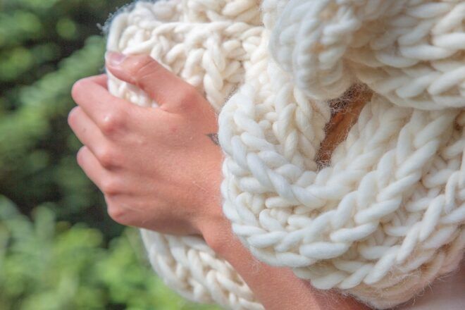 Hands touching a white wool scarf