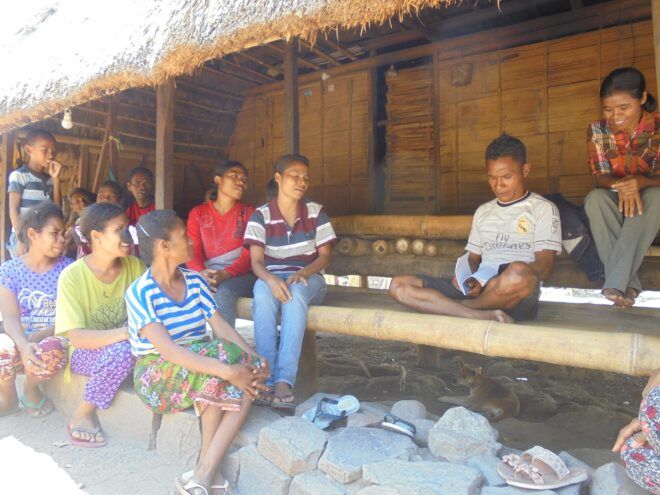 Indonesians huddled under a hut talking to each other