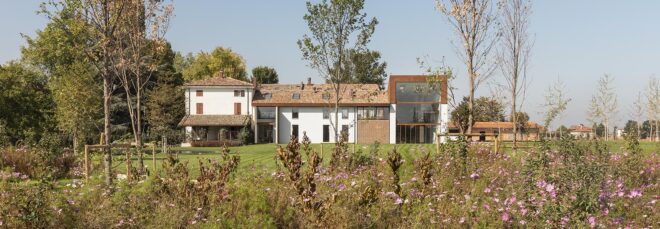 A landscape of a home with wildflowers in front of it.