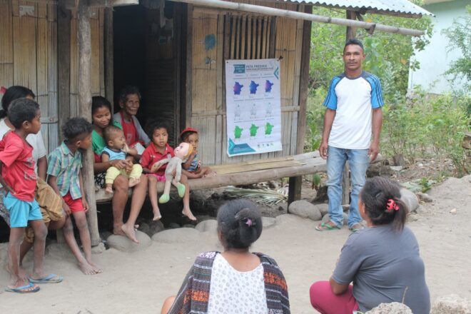 A man teaching environmental preparedness to a group of villagers