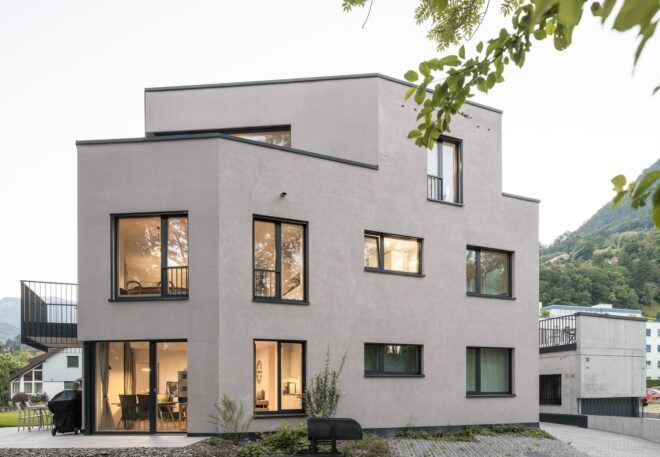 A whitish pinkish house that is two floors and multiple windows