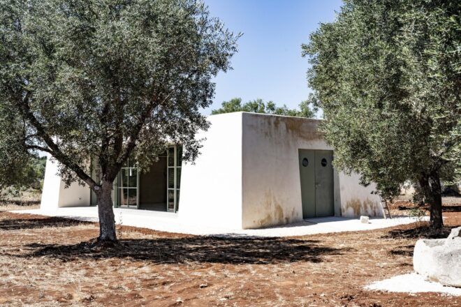 A white rectangular building with green trees scattered around it