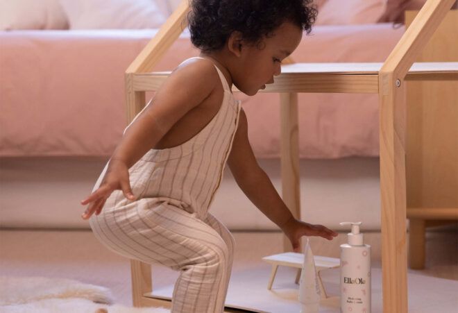 A toddler reaching for a bottle of lotion.