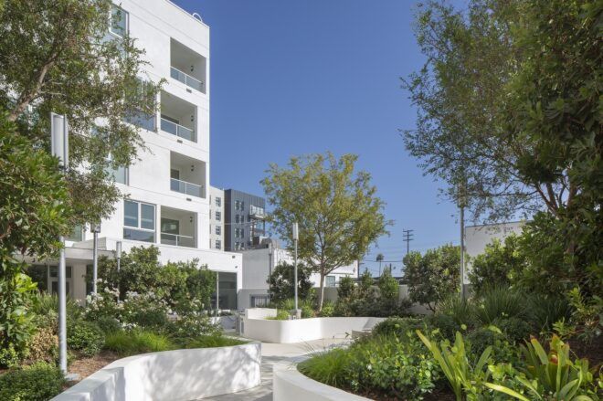A white building on the left side with trees on the right side