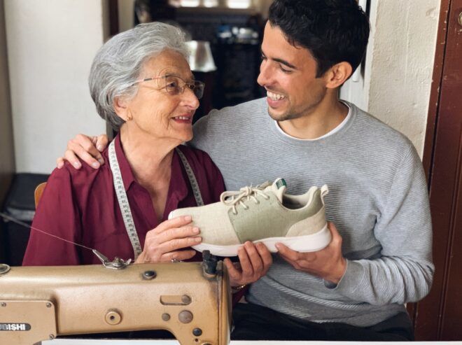 A grandmother and grandson smiling at each other and holding a shoe between them