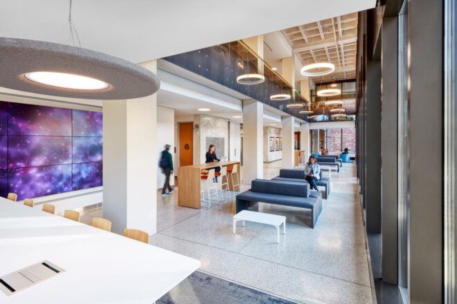 A lobby area where people sit on sofas and at tables, with a galaxy mural to the left.