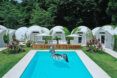 A pool surrounded by several white glamping domes.