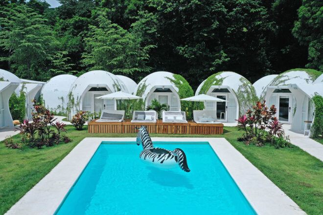 A pool surrounded by several white glamping domes.