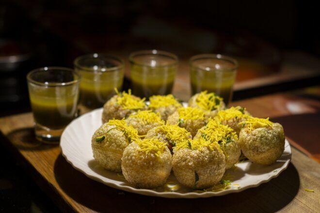 A white plate holding fried balls sprinkled with garnish