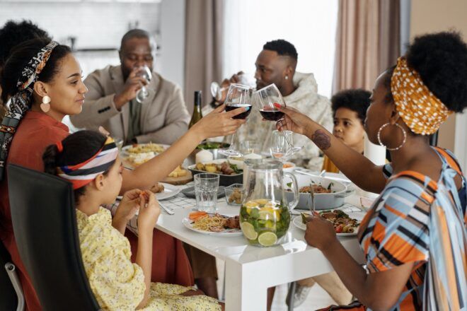 A family cheering with wine glasses, sitting around a table