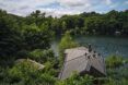 A home peaking out from the trees by a lake.