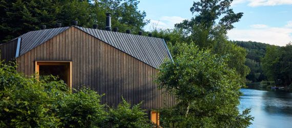 A home peaking out from the trees by a lake.