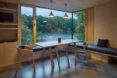 A minimalist dining room with wood floors, walls, table and chairs next to a large window.