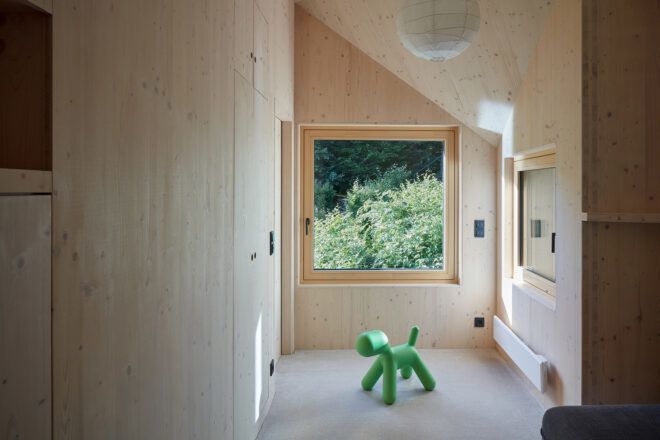 A wood halway with a green dog-like toy on the floor.