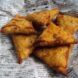 Triangle-shaped deep fried food wrapped in a newspaper