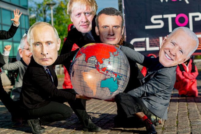 Protestors wearing cardboard masks of various world leaders protest with an inflatable globe toy.