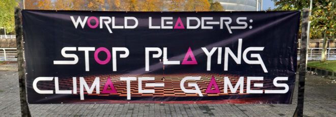 A black sign reading "World leaders: stop playing climate games."