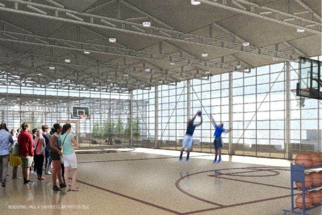 An indoor basketball court filled with people and kids playing on the court