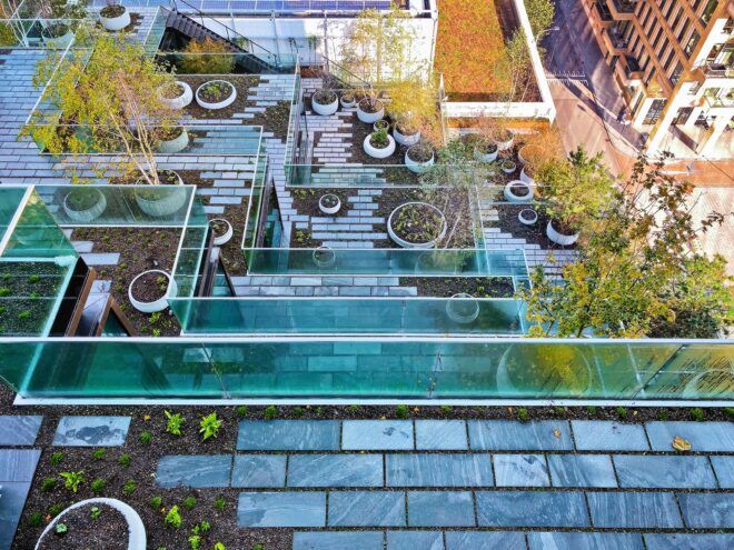 A terrace top that has potted trees within a glass fence