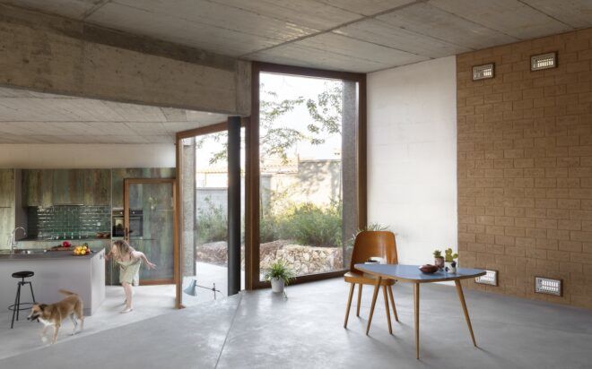A living room area that divides into two levels with the upper level having a table and chair and the lower level a kitchen area