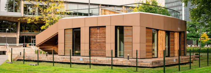 Wood clad house with tan-colored solar panels on the facades and an open roof garden