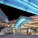 An inside pavilion with blue lightings above and staircases where people are walking around