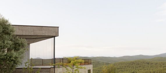 A building overlooks a mountain and forest range